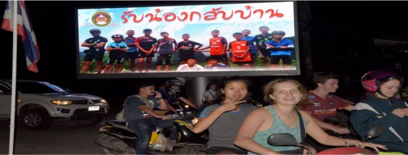 Motoristas passam por cartaz com foto dos integrantes do time Wild Boar e seu técnico com a mensagem “bem-vindos irmãos”, em Chiang Rai, após o resgate do grupo na caverna Tham Luang, na terça-feira (10)